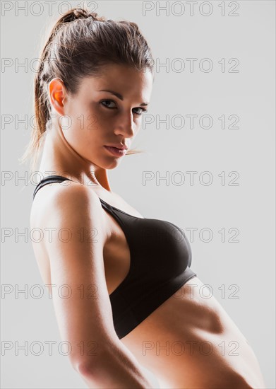 Portrait of young woman exercising, studio shot. Photo : Mike Kemp