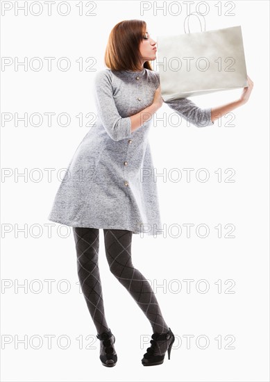 Young woman holding shopping bag, studio shot. Photo: Mike Kemp