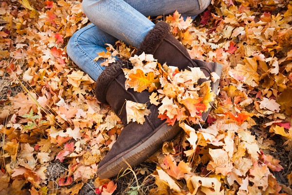 Legs of young woman lying on autumn leaves. Photo : Mike Kemp