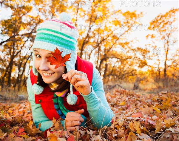 Portrait of smiling young woman lying on autumn leaves . Photo: Mike Kemp