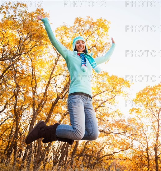 Happy young woman jumping in autumn forest. Photo: Mike Kemp