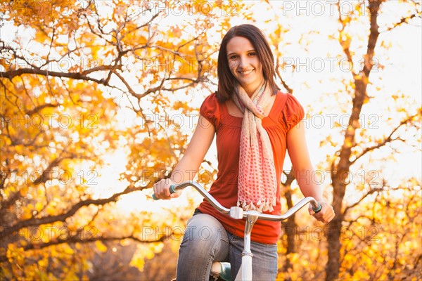 Happy young woman with bicycle in autumn in forest. Photo : Mike Kemp