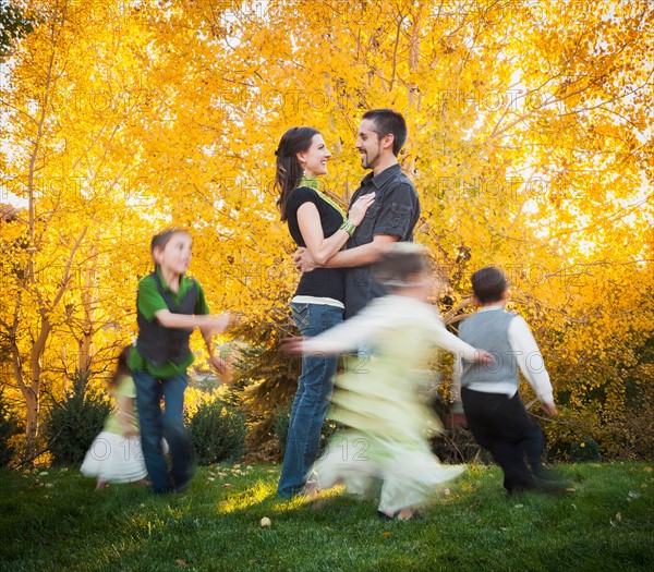 Bountiful, Family with children (2-3, 4-5, 6-7, 8-9) dancing in garden at autumn. Photo: Mike Kemp