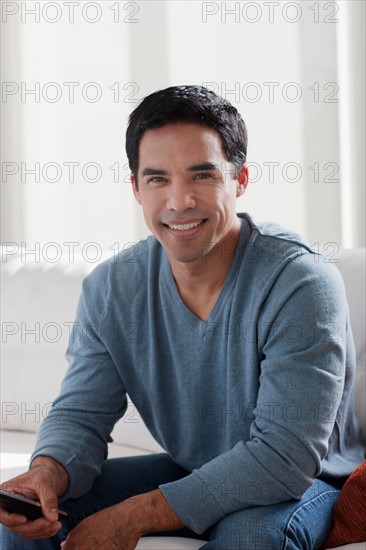 Portrait of smiling mid adult man sitting on sofa. Photo : Dan Bannister