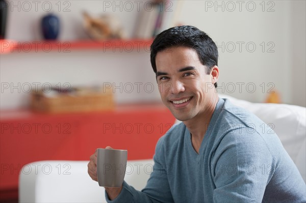 Portrait of man drinking coffee in living room. Photo : Dan Bannister