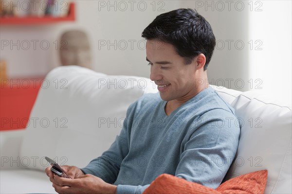 Man texting in living room. Photo : Dan Bannister