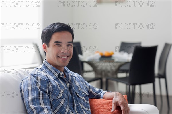 Portrait of man sitting in living room. Photo : Dan Bannister