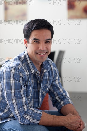 Portrait of man sitting in living room. Photo : Dan Bannister