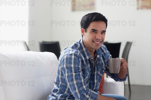 Portrait of man drinking coffee in living room. Photo: Dan Bannister