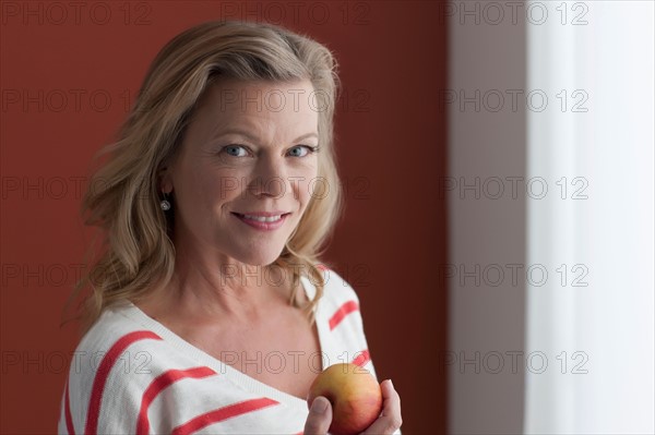 Portrait of mature woman eating apple. Photo : Dan Bannister