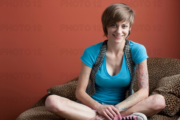 Portrait of young woman sitting on sofa. Photo : Dan Bannister