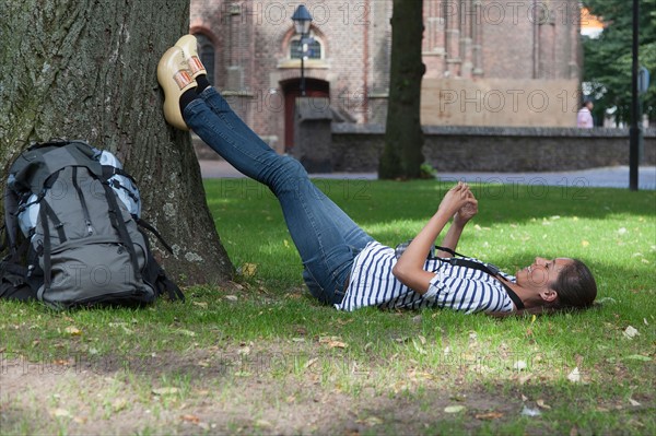 Young woman with backpack lying on grass. Photo : Jan Scherders