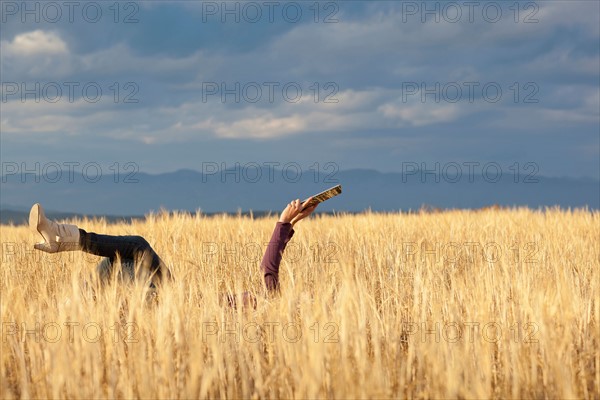 Woman lying in field holding digital tablet. Photo : Noah Clayton