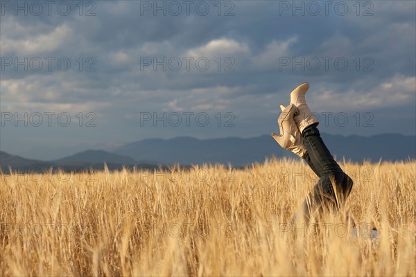 Woman lying in scenic field with feet in air. Photo : Noah Clayton