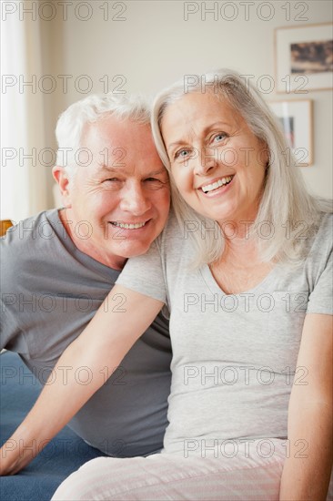 Senior couple sitting on bed in close embrace. Photo: Rob Lewine