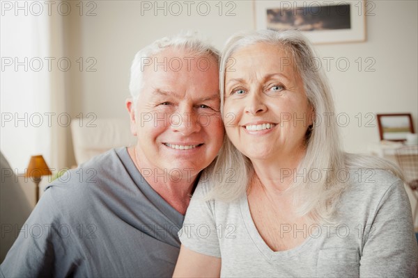 Senior couple sitting on bed in close embrace. Photo : Rob Lewine