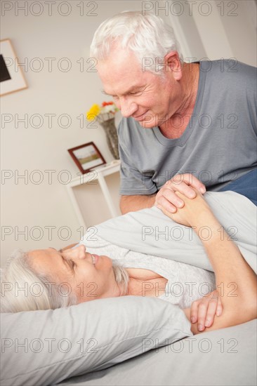 Bedroom scene with senior man holding wife's hand. Photo : Rob Lewine