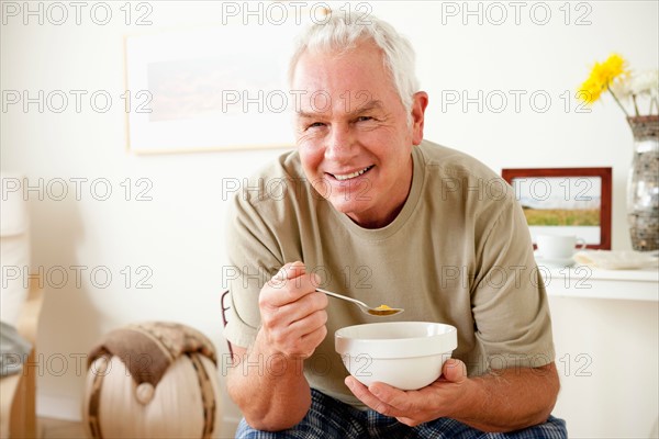 Senior man eating cereal from bowl. Photo : Rob Lewine