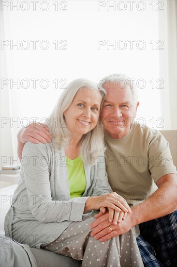 Portrait of senior couple sitting in bedroom. Photo : Rob Lewine