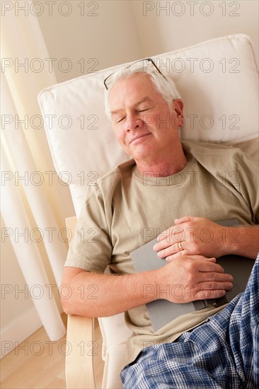 Senior man taking nap and holding book. Photo: Rob Lewine