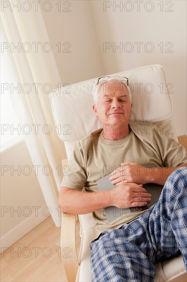 Senior man taking nap and holding book. Photo : Rob Lewine