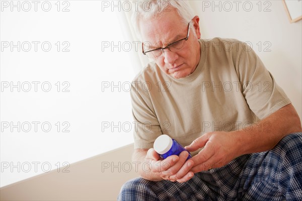 Senior man holding medicine flask. Photo: Rob Lewine