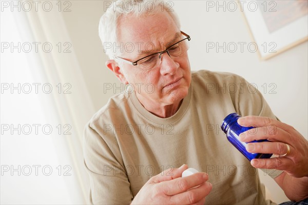 Senior man holding medicine flask. Photo : Rob Lewine