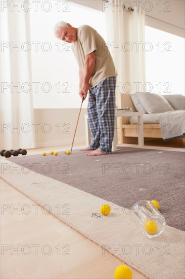 Senior man playing mini golf at home. Photo : Rob Lewine