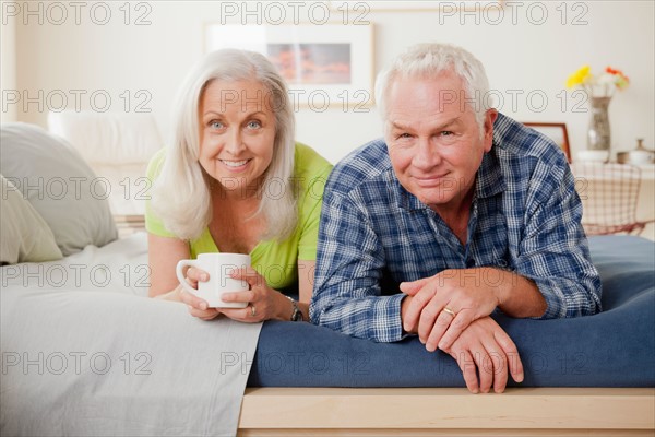Portrait of senior couple laying on bed. Photo : Rob Lewine