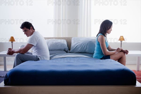 Mid adult couple after quarrel sitting on bed. Photo : Rob Lewine