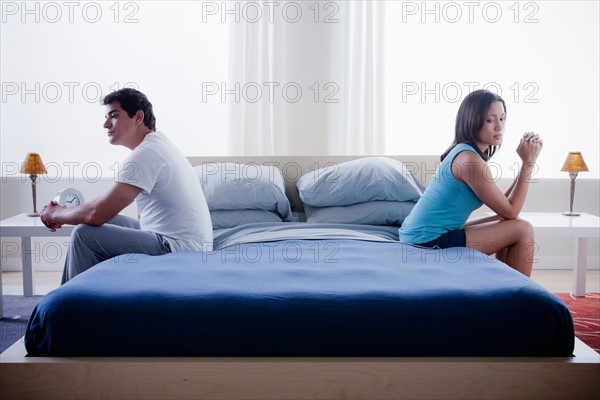 Mid adult couple after quarrel sitting on bed. Photo : Rob Lewine