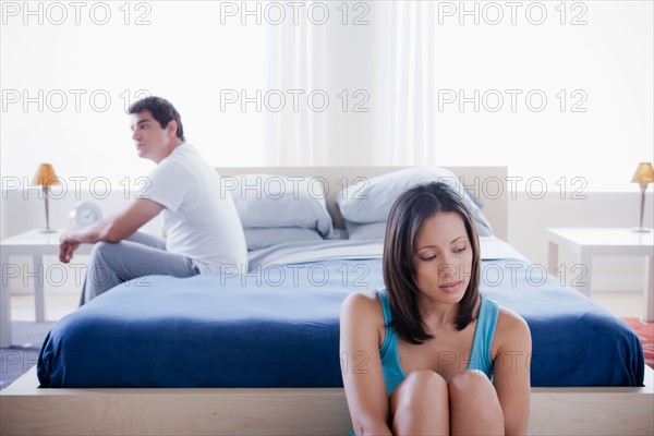 Mid adult couple after quarrel sitting in bedroom. Photo : Rob Lewine