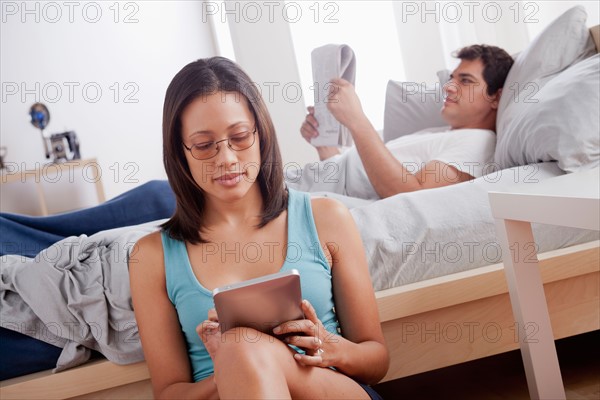 Woman using digital tablet and man reading newspaper. Photo: Rob Lewine