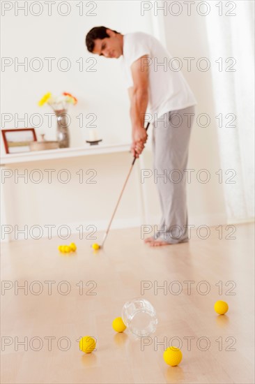 Man dressed in pajamas playing mini golf at home. Photo : Rob Lewine