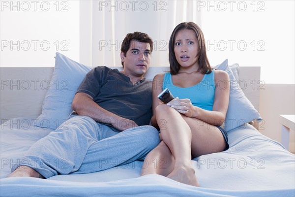 Couple sitting on bed and watching tv. Photo : Rob Lewine