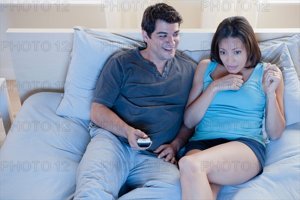 Couple sitting on bed watching television. Photo: Rob Lewine