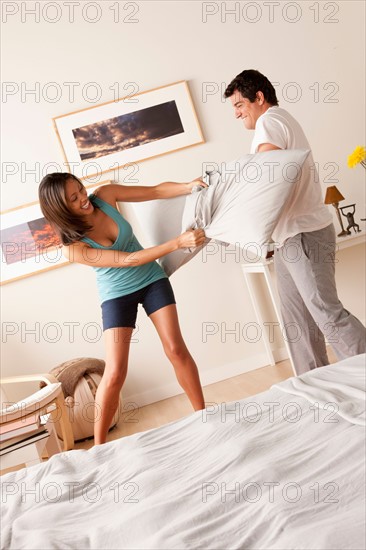 Couple fighting with pillow in bedroom. Photo: Rob Lewine
