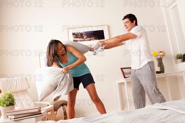 Couple fighting with pillow in bedroom. Photo: Rob Lewine