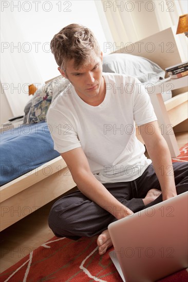Man sitting on floor using laptop. Photo : Rob Lewine