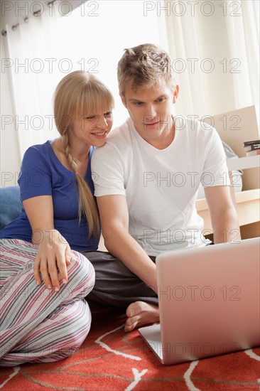 Couple sitting on floor using laptop. Photo: Rob Lewine