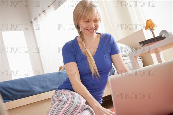 Portrait of woman sitting on floor using laptop. Photo : Rob Lewine