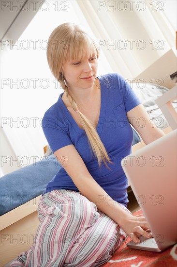 Portrait of woman sitting on floor using laptop. Photo : Rob Lewine