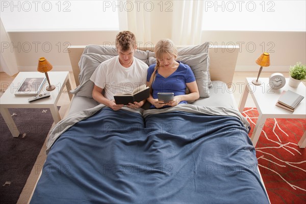 Elevated view of couple sitting in bed reading. Photo: Rob Lewine
