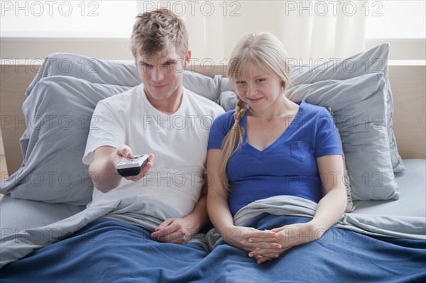 Couple watching television in bed. Photo : Rob Lewine