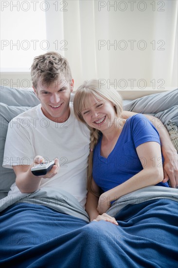 Couple watching television in bed. Photo : Rob Lewine