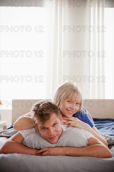 Woman lying atop man in bed. Photo : Rob Lewine