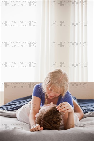 Woman lying atop man in bed. Photo : Rob Lewine