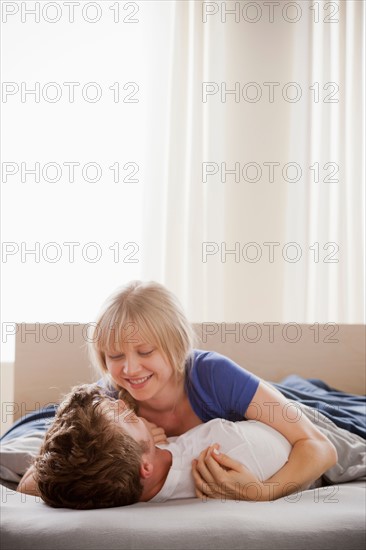 Woman lying atop man in bed. Photo : Rob Lewine