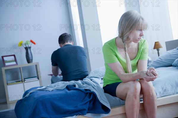 Woman and man sitting on bed back to back. Photo : Rob Lewine