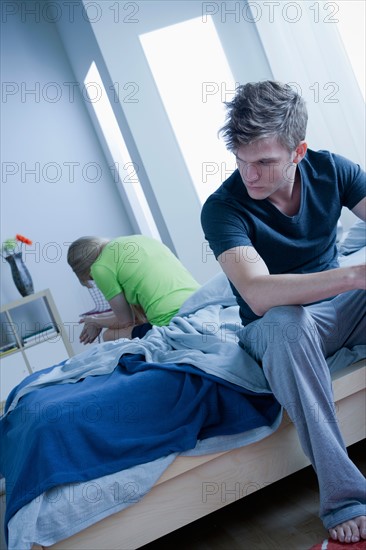 Woman and man sitting on bed back to back. Photo : Rob Lewine